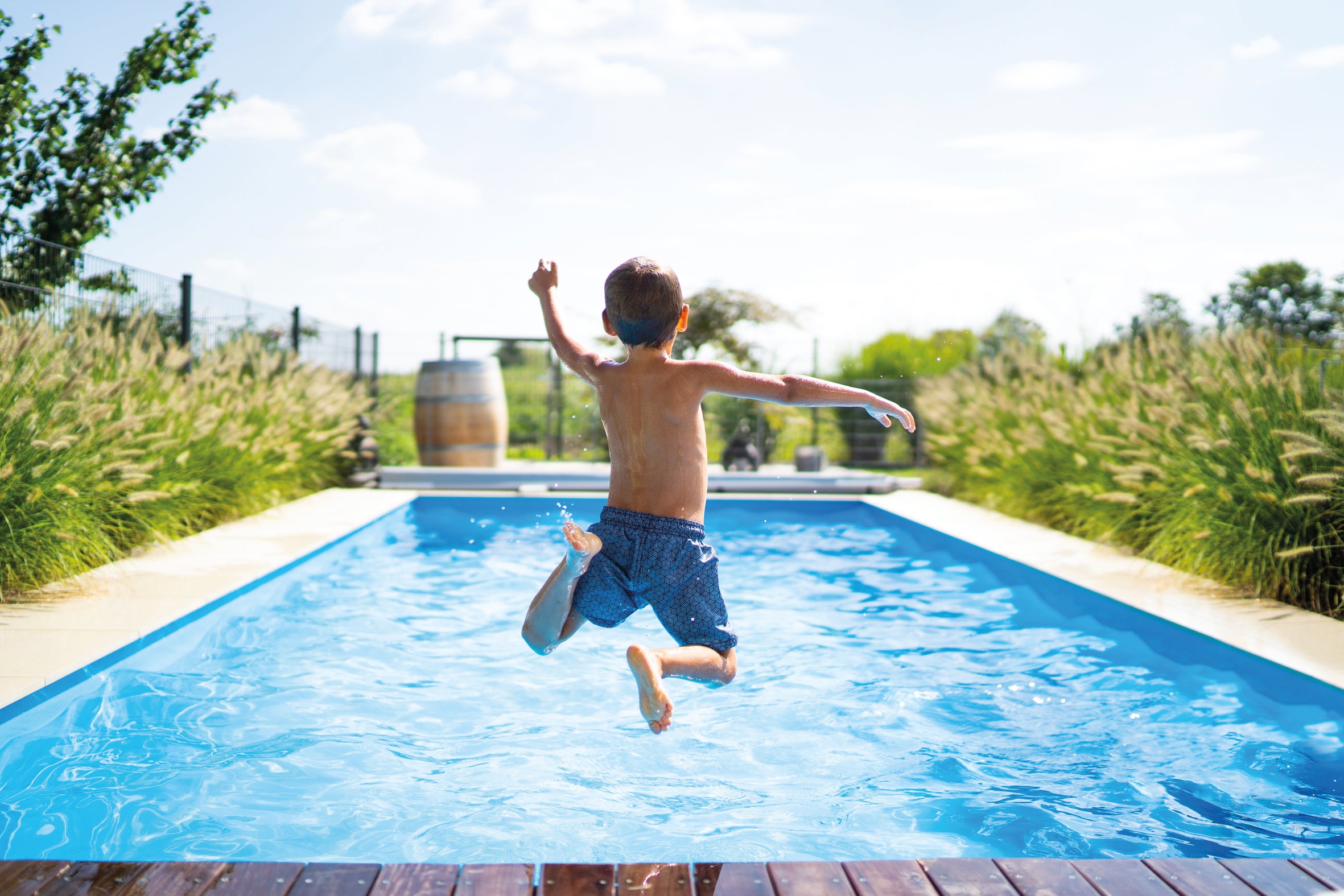 Niño saltando hacia la piscina